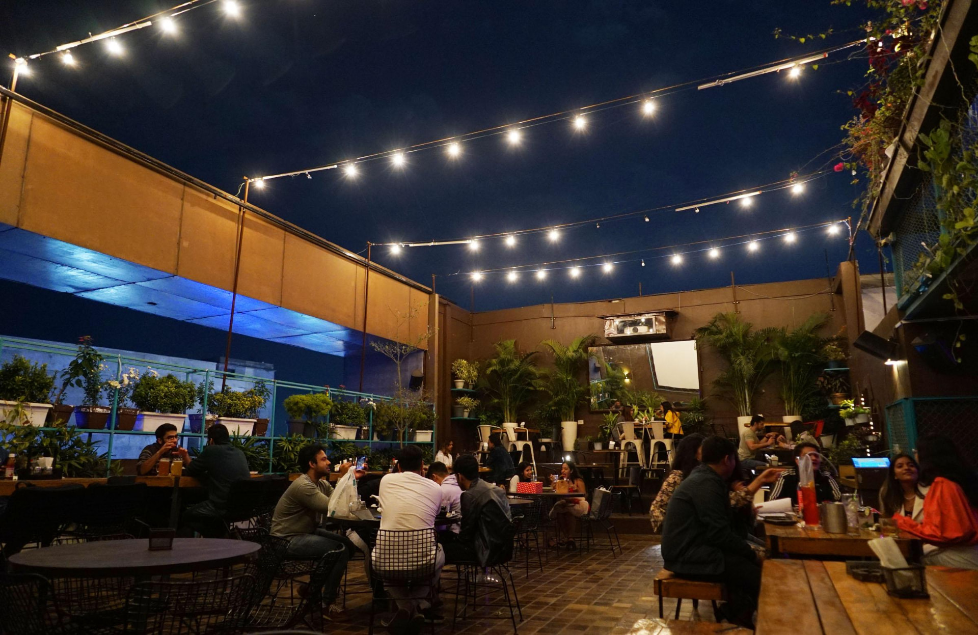 Rooftop cafe seating at night under strings of warm lights
