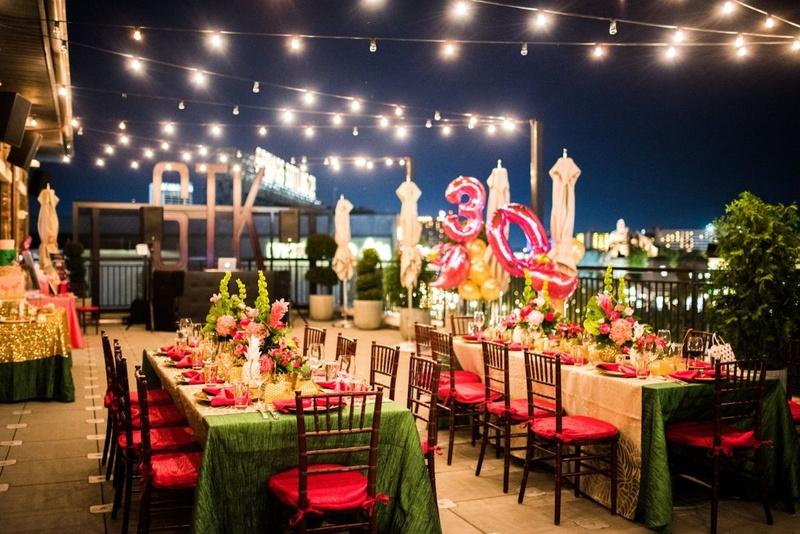 Rooftop dinner tables decorated with flowers and balloons at night