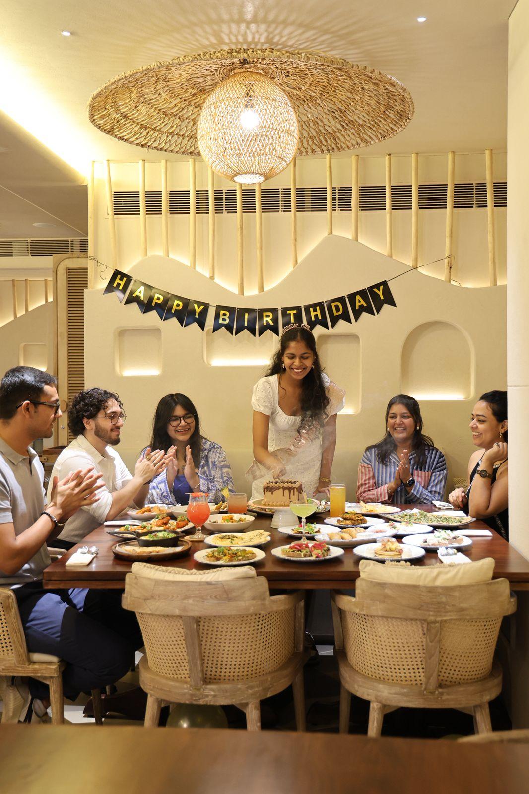 Friends celebrating a birthday around a long table of food